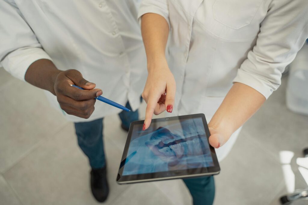 Two medical professionals analyzing a dental x-ray on a tablet. Collaborative healthcare setting.